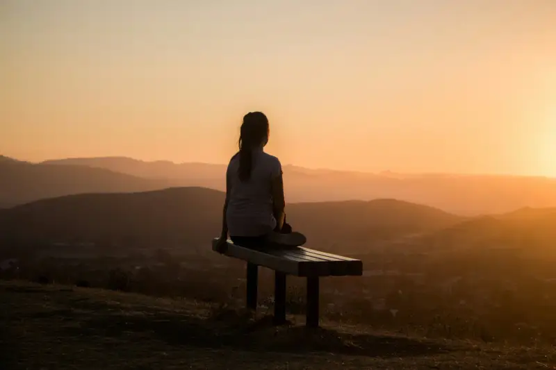 Mulher meditando ao entardecer — interpretação de sonhos e significado do subconsciente